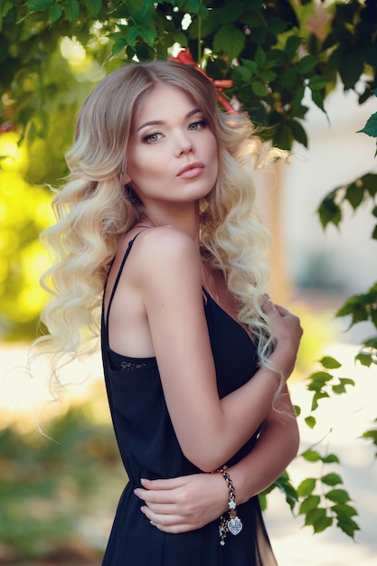 Young beautiful woman in long pink evening dress walking path in park. Fashion style portrait of gorgeous beautiful girl outdoors