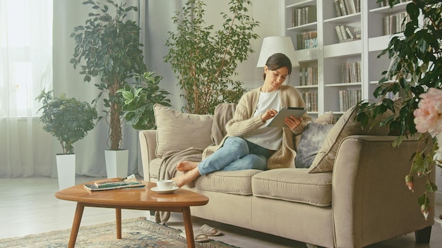 Young beautiful woman looking at her tablet in her apartment