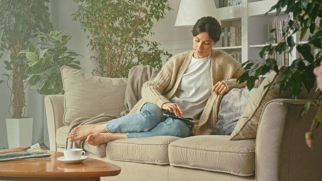 Young beautiful woman looking at her tablet in her apartment