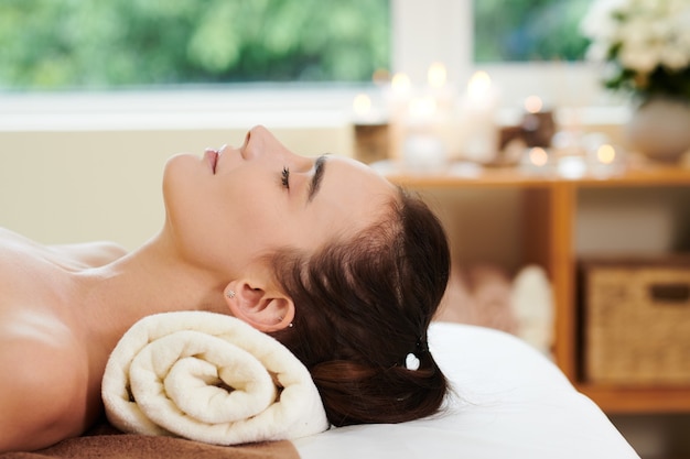 Young beautiful woman lying with eyes closed and relaxing in spa