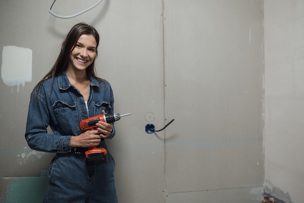 Photo young beautiful woman makes repairs in the apartment the girl makes repairs at home on her own paint...