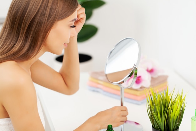 Young beautiful woman making make-up near mirror