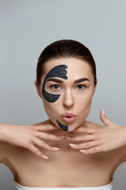 Young beautiful woman in a mask for the face of the therapeutic
black clay beauty face skin care