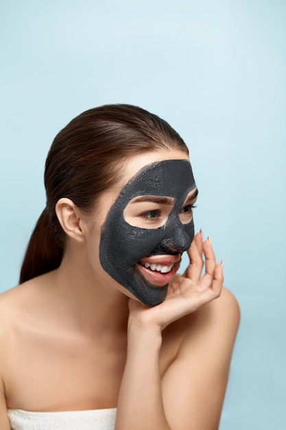 Young beautiful woman in a mask for the face of the therapeutic black clay Girl mode Beauty face