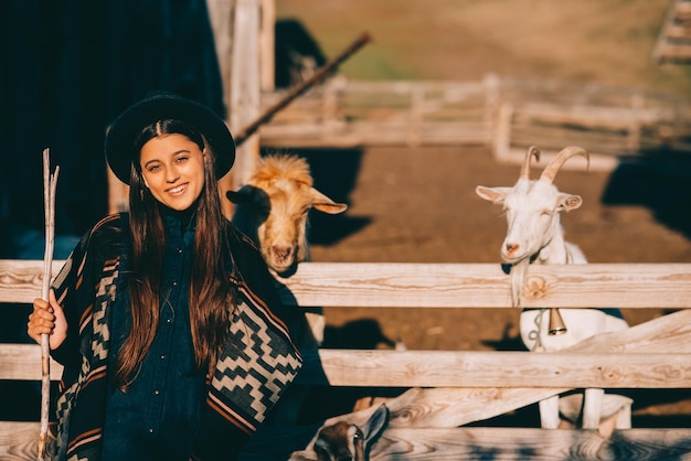 Foto una giovane bella donna vicino a un recinto con le capre