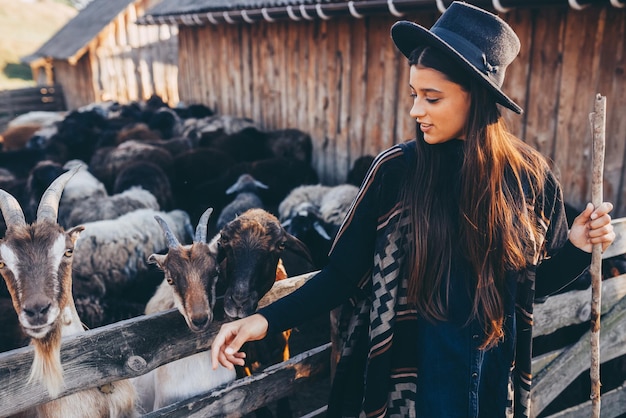 Foto una giovane bella donna vicino a un recinto con le capre