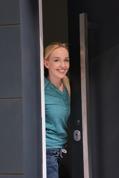 Photo young beautiful woman opening her house door to welcome people