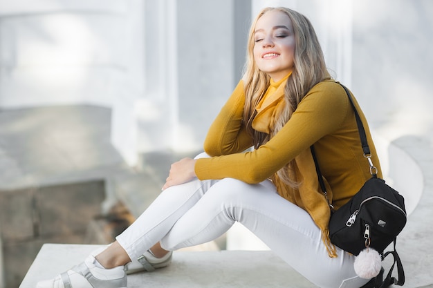 Young beautiful woman  outdoors. Closeup portrait of cheerful ladyon spring or autumn background. Girl with backpack.