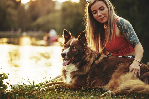 公園で彼女のかわいい犬をかわいがって若い美しい女性