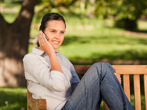 Young beautiful woman phoning on the bench