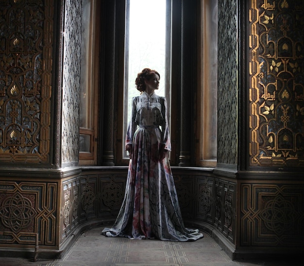 Young beautiful woman in pink dress posing in luxury palace