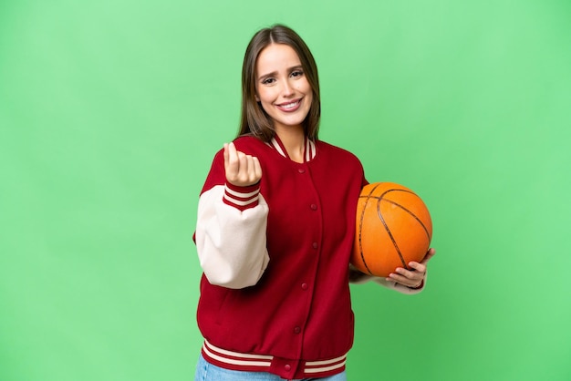 Young beautiful woman playing basketball over isolated chroma key background making money gesture