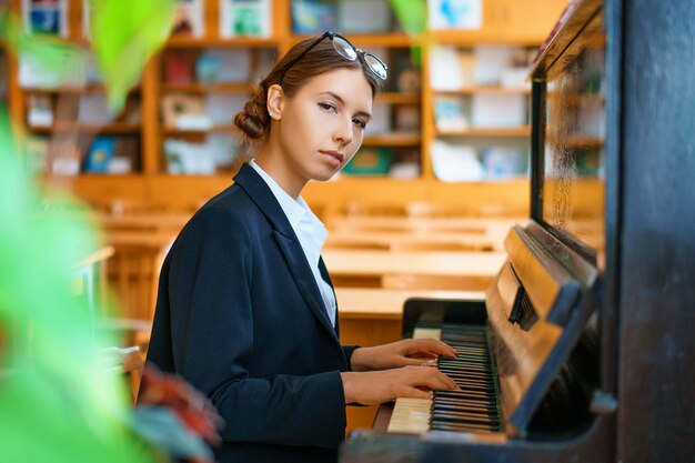 Young beautiful woman playing the piano in class