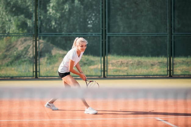 Молодая красивая женщина, играя в теннис на корте. Здоровый спортивный образ жизни