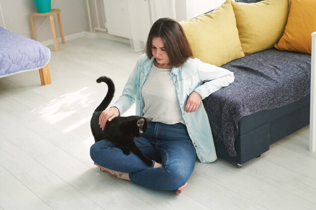 Young beautiful woman playing with her pet black cat