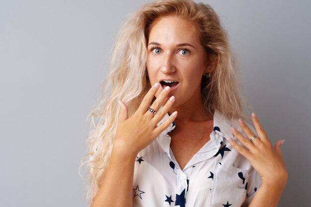 Young beautiful woman portrait being excited and amazed over gray background