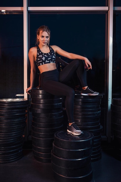 Young beautiful woman posing in a gym outfit. Young healthy girl with a perfect figure.