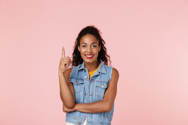 La giovane bella donna che posa isolata sopra l'indicazione rosa della parete ha idea