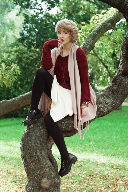 Молодая красивая женщина позирует на дереве Гламурный модный портрет Осенний парк