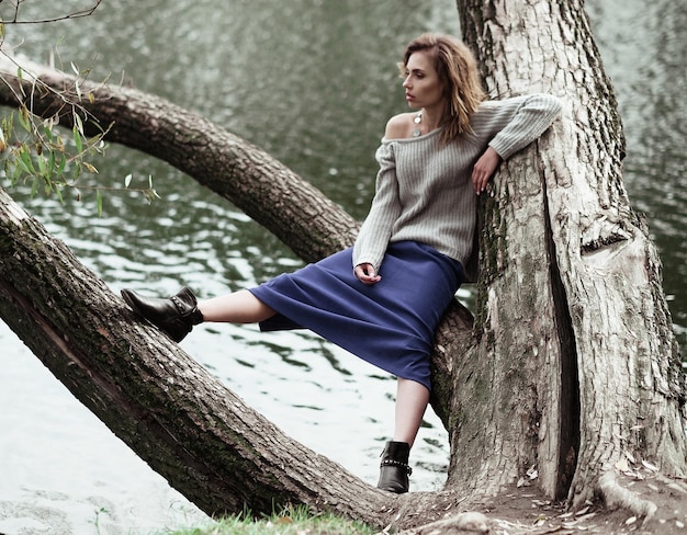 Young beautiful woman posing on a tree Glamour fashion portrait Autumn park