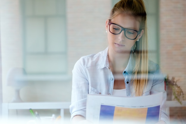 Photo young beautiful woman reading newspaper at home.