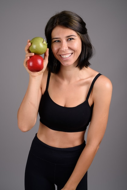 Young beautiful woman ready for gym against gray background