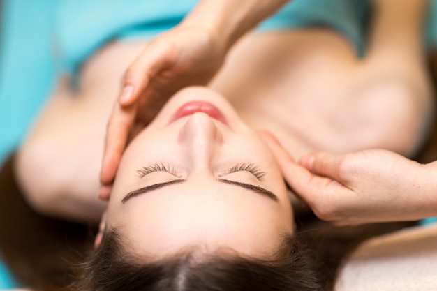 Photo young beautiful woman receiving head face massage in beauty spa