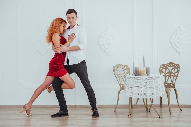 Young beautiful woman in a red dress and a man dancing isolated on a white background.