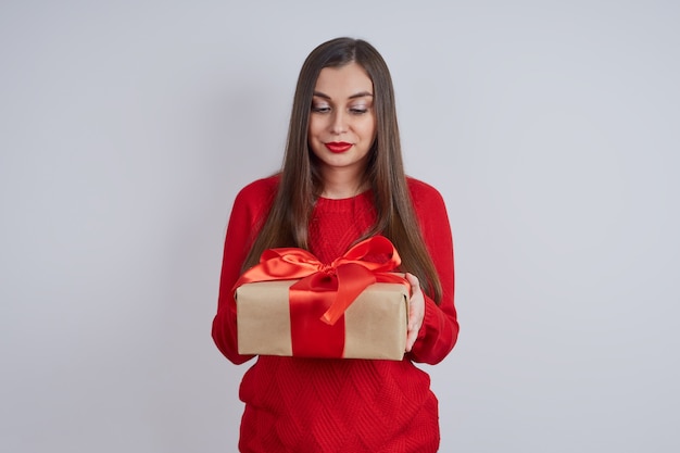 Young beautiful woman in a red sweater, holding a gift box