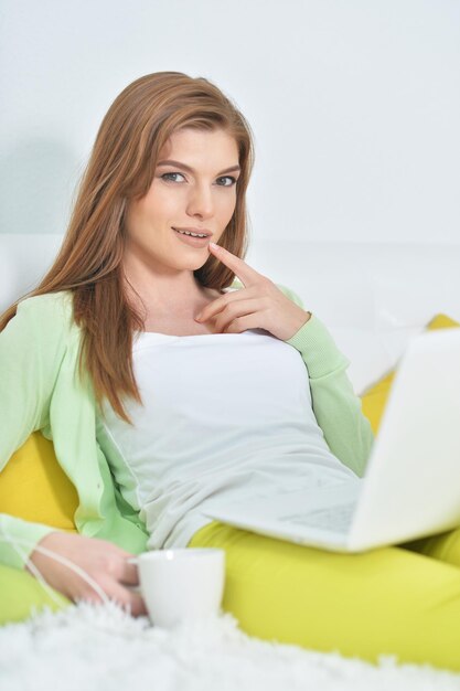 Young beautiful woman relaxing in bed with laptop