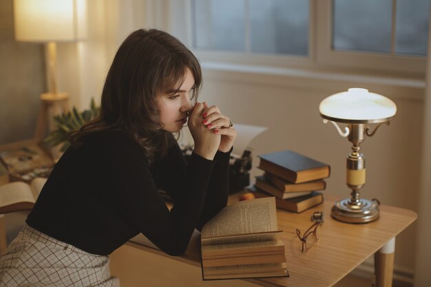 Young beautiful woman relaxing at home in the cozy evening and reading book