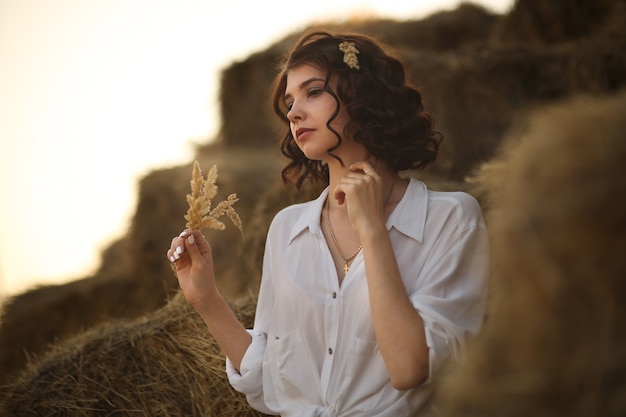 Young beautiful woman in a rustic style sits resting in the countryside