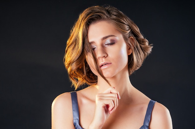 Young and beautiful woman short haircut hair curly hair and evening metallic make-up perfect skin studio shot on black background.fashion model sensual look.