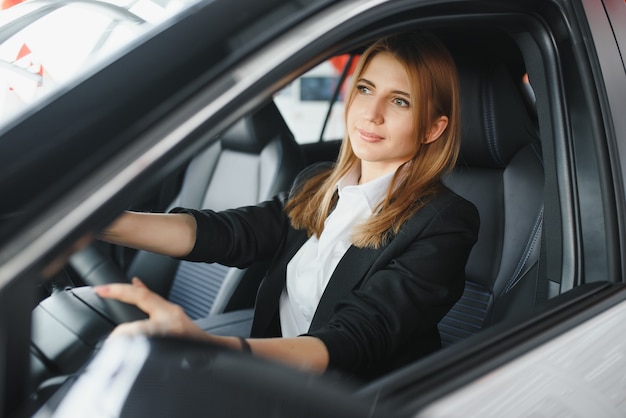 Young beautiful woman showing her love to a car in a car showroom