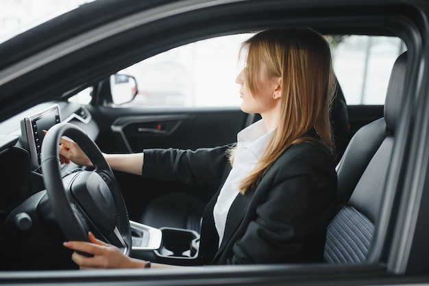 車のショールームで車に彼女の愛を示す若い美しい女性