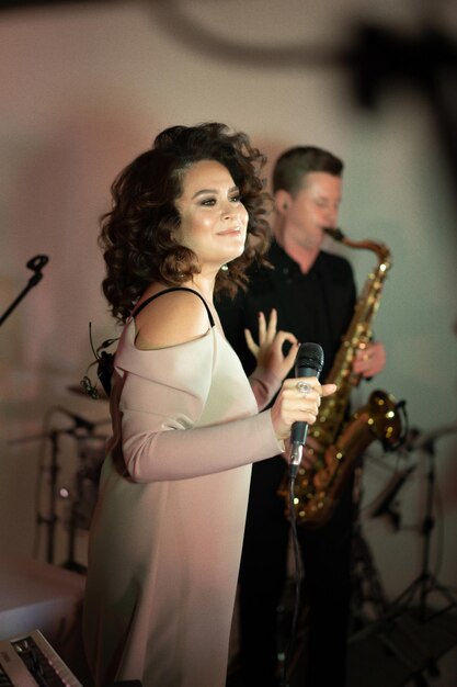 young beautiful woman singer on stage singing into microphone