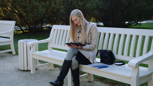 Young beautiful woman sits on a bench in the park