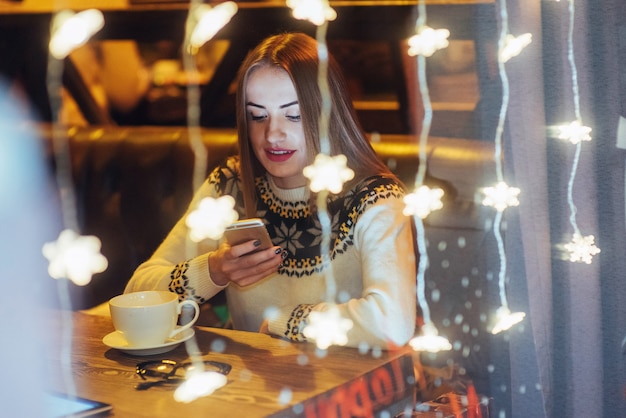 Young beautiful woman sitting in cafe, drinking coffee. Christmas, new year, Valentines day, winter holidays 