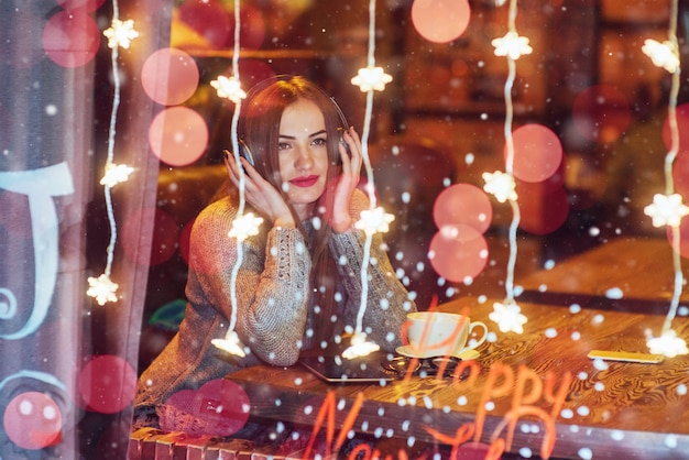 Photo young beautiful woman sitting in cafe, drinking coffee. model listening to music.