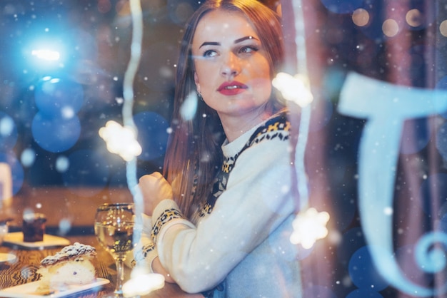 Young beautiful woman sitting in cafe, drinking wine. Christmas, new year, Valentines day, winter holidays 