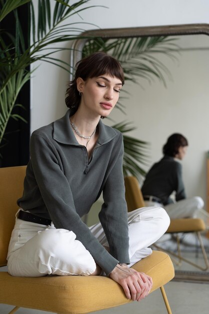 Photo young beautiful woman sitting in a chair in the studio wearing a sweater