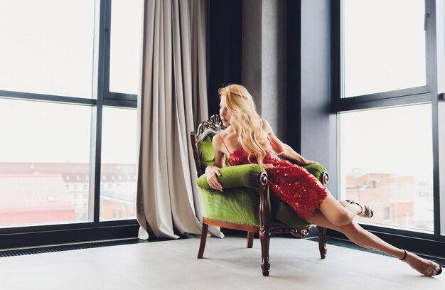 young beautiful woman sitting in a vintage chair and looking at the camera relaxed posture