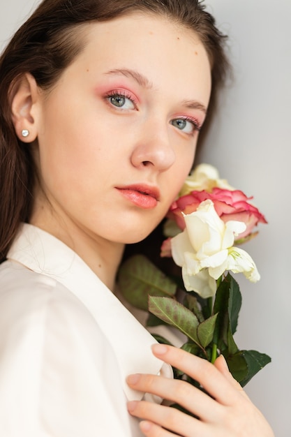 Young beautiful woman smelling a bunch of red roses. fashion interior photo of beautiful smiling woman with dark hair holding a big bouquet of red roses in Valentine's day
