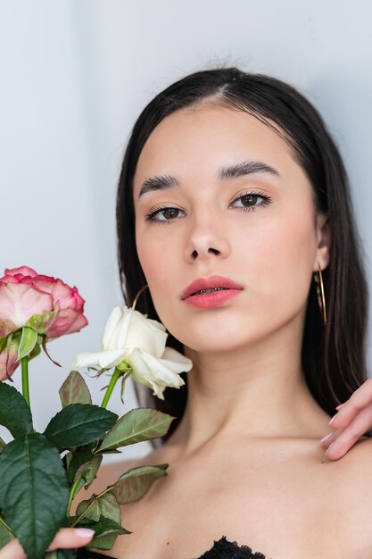 Young beautiful woman smelling a bunch of red roses fashion interior photo of beautiful smiling woman with dark hair holding a big bouquet of red roses in Valentines day