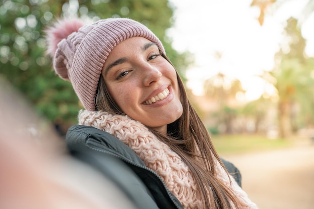 Young beautiful woman smiling taking selfie photo at university campus trendy girl with winter hat