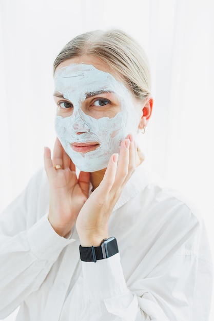 Photo young beautiful woman smiling with cream on her face care mask for facial skin