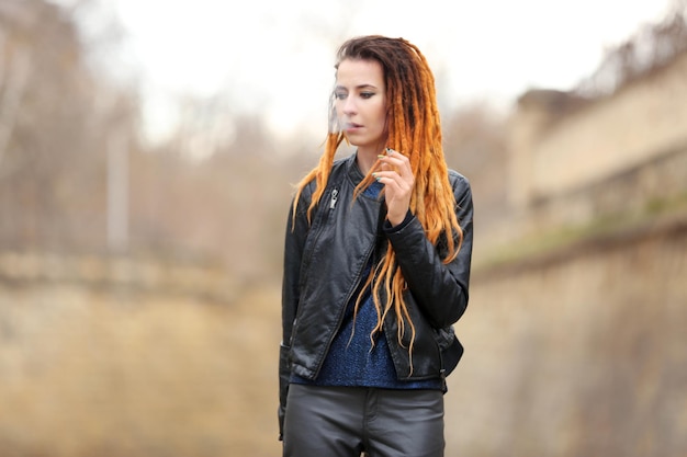 Young beautiful woman smoking weed on blurred background