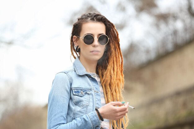 Young beautiful woman smoking weed on blurred background