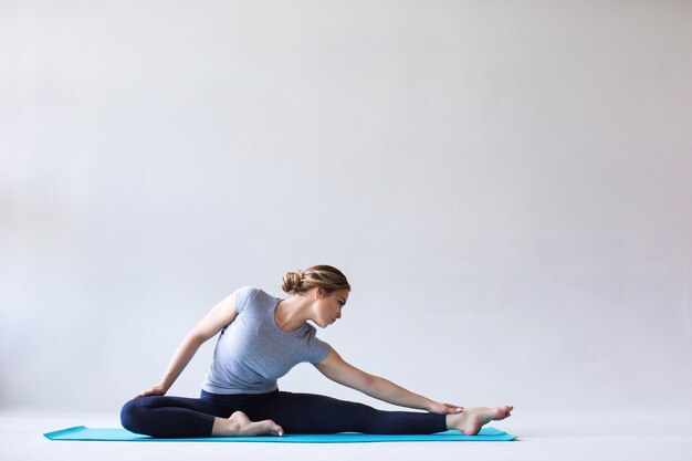 Giovane bella donna in abiti sportivi facendo stretching