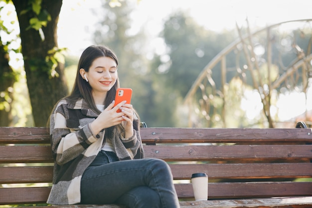 Young beautiful woman standing on a bench using the laptop